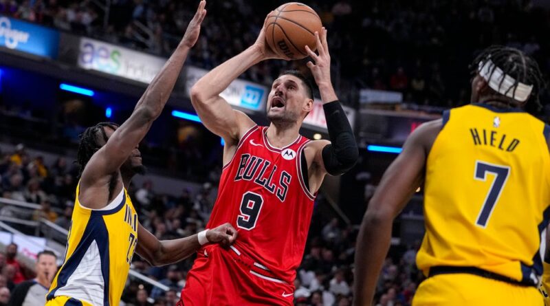 Chicago Bulls center Nikola Vucevic (9) shoots between Indiana Pacers forward Aaron Nesmith (23) and guard Buddy Hield (7) during the second half of an NBA